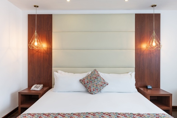 a hotel room with a bed and two lamps hanging from the ceiling