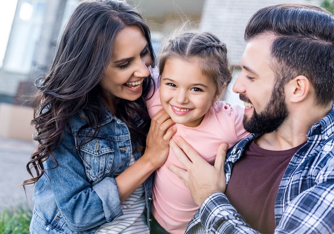 a man and woman are holding a little girl and smiling