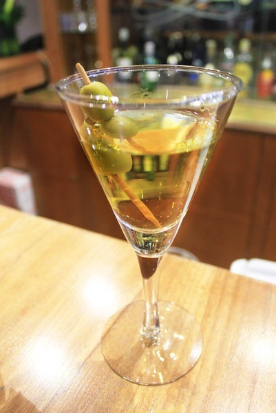 a martini with olives and a toothpick in it