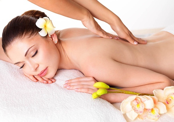 a woman with a flower in her hair is getting a massage