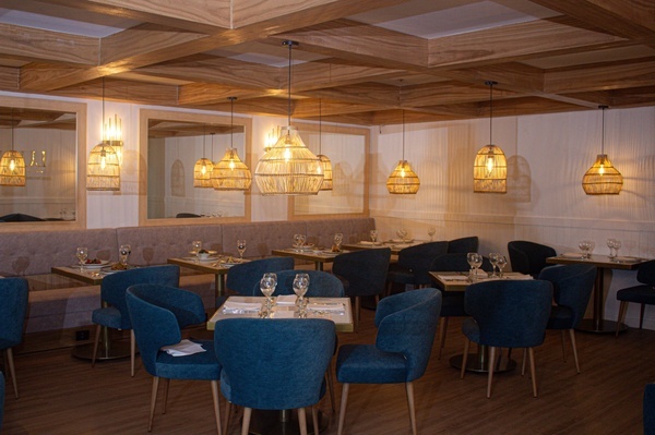 a restaurant with blue chairs and tables with glasses on them