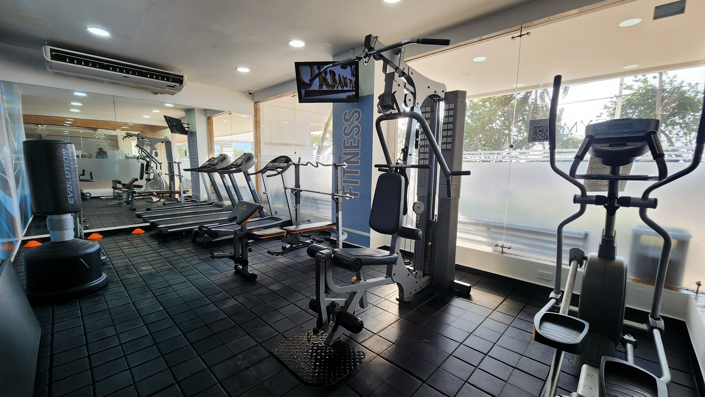 a gym with ellipticals and treadmills and a tv on the wall