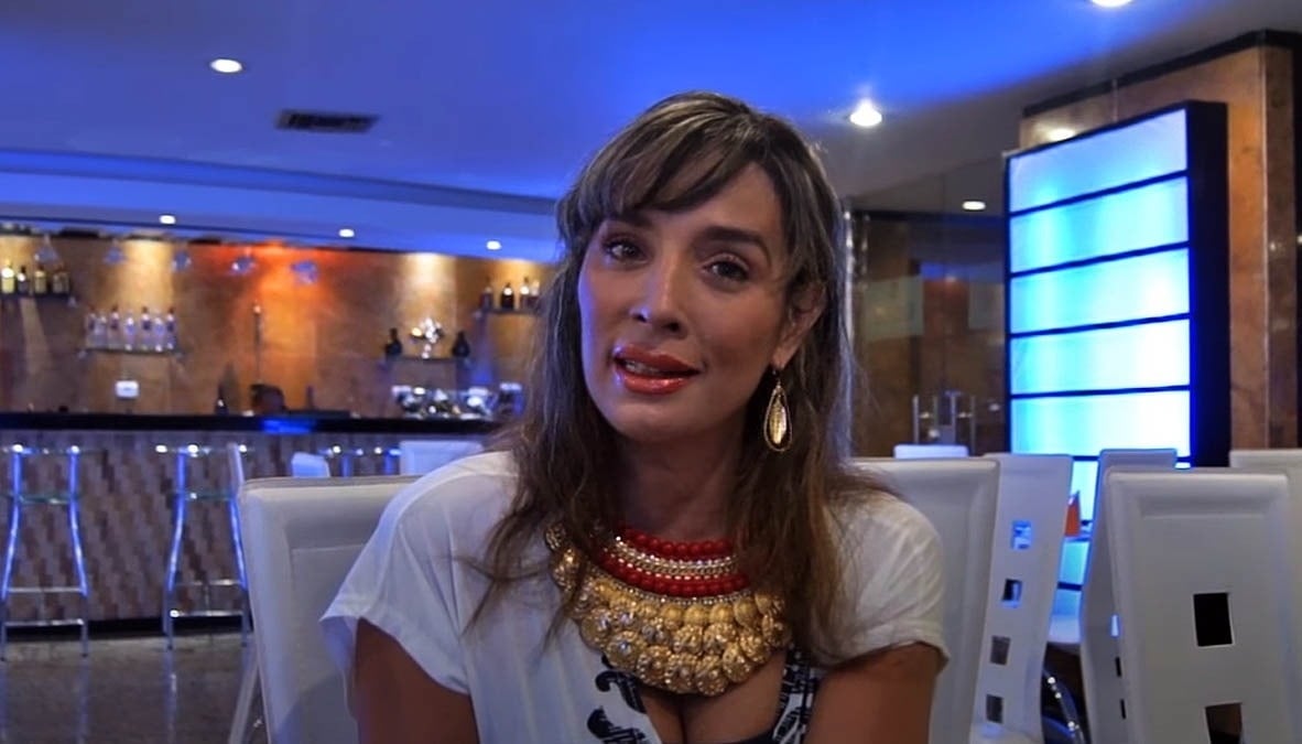uma mulher está sentada em uma mesa com um colar vermelho e dourado