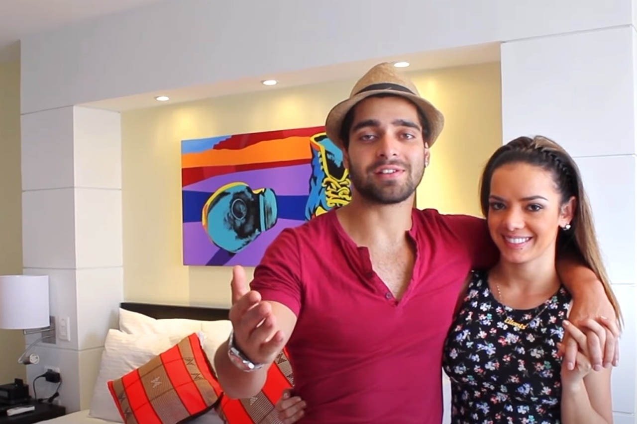 um homem e uma mulher estão em um quarto com uma pintura ao fundo