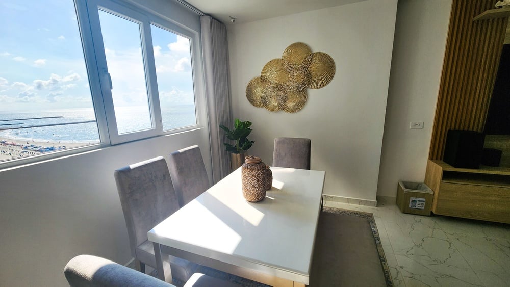 uma sala de jantar com mesa e cadeiras e uma janela com vista para o oceano