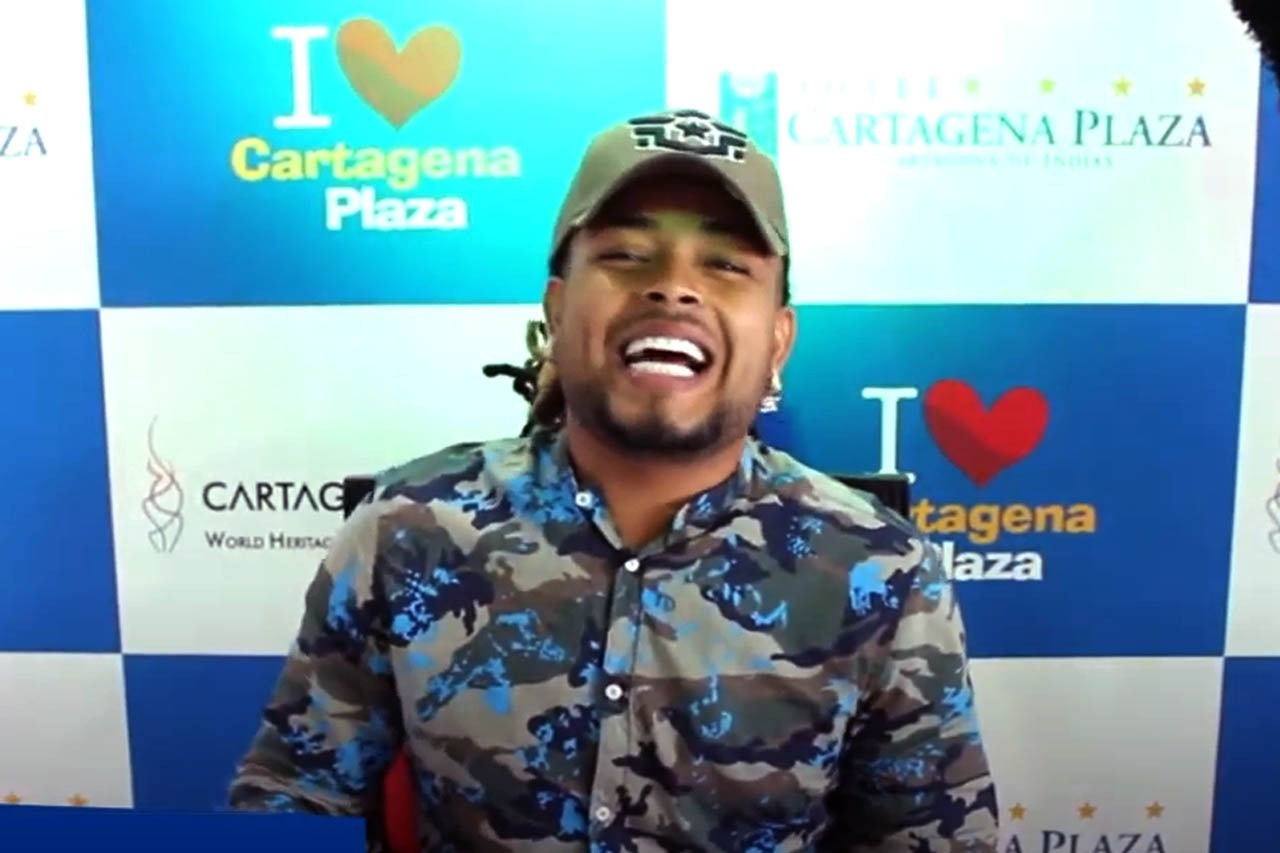 um homem sorrindo em frente a uma parede que diz cartagena plaza