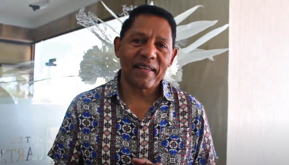 un hombre con una camisa azul y blanca está de pie frente a una ventana con la palabra nta impresa en ella