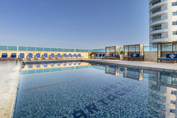 uma piscina com cadeiras ao redor e uma cama ao lado