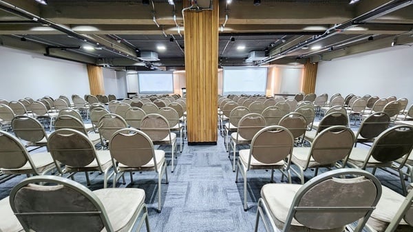 una sala de conferencias llena de sillas y una pantalla