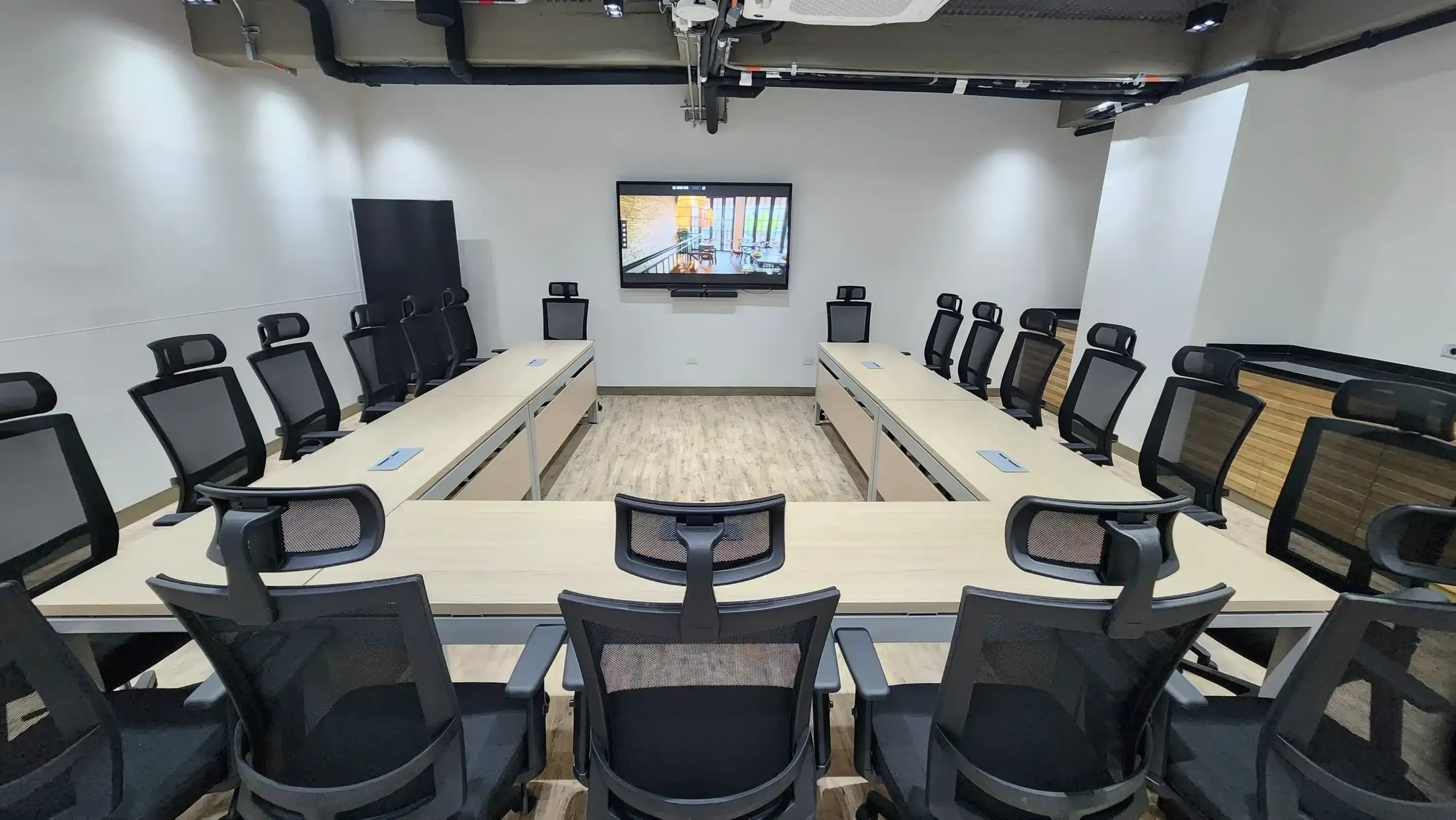 una sala de conferencias con mesas y sillas y una pantalla en la pared