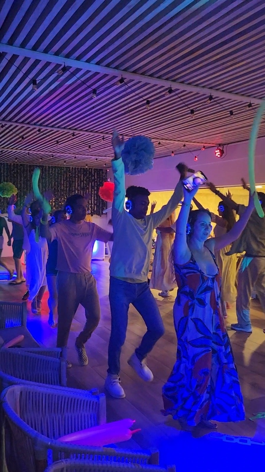 um grupo de pessoas está dançando em uma sala com luzes azuis