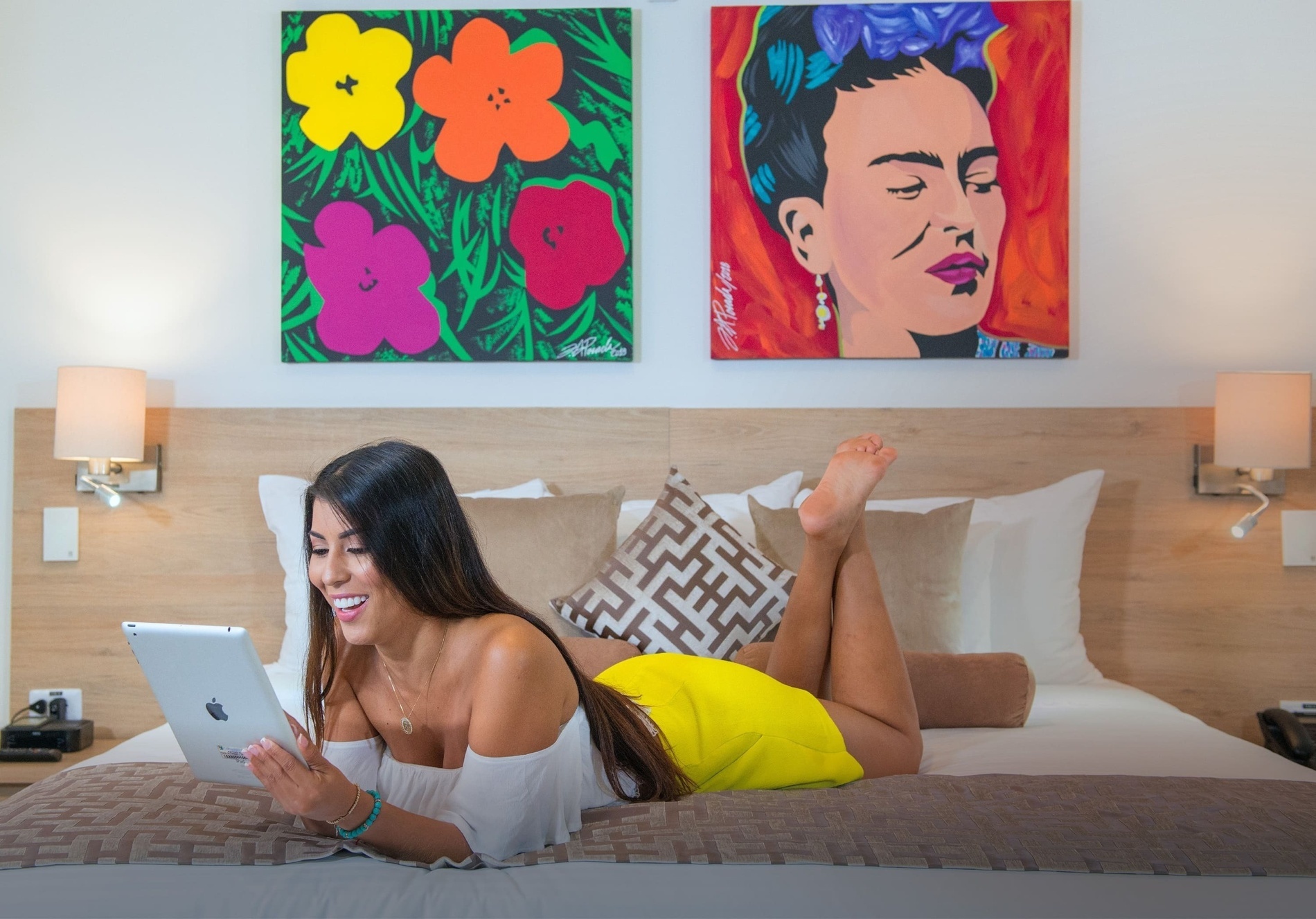 a woman laying on a bed looking at a tablet