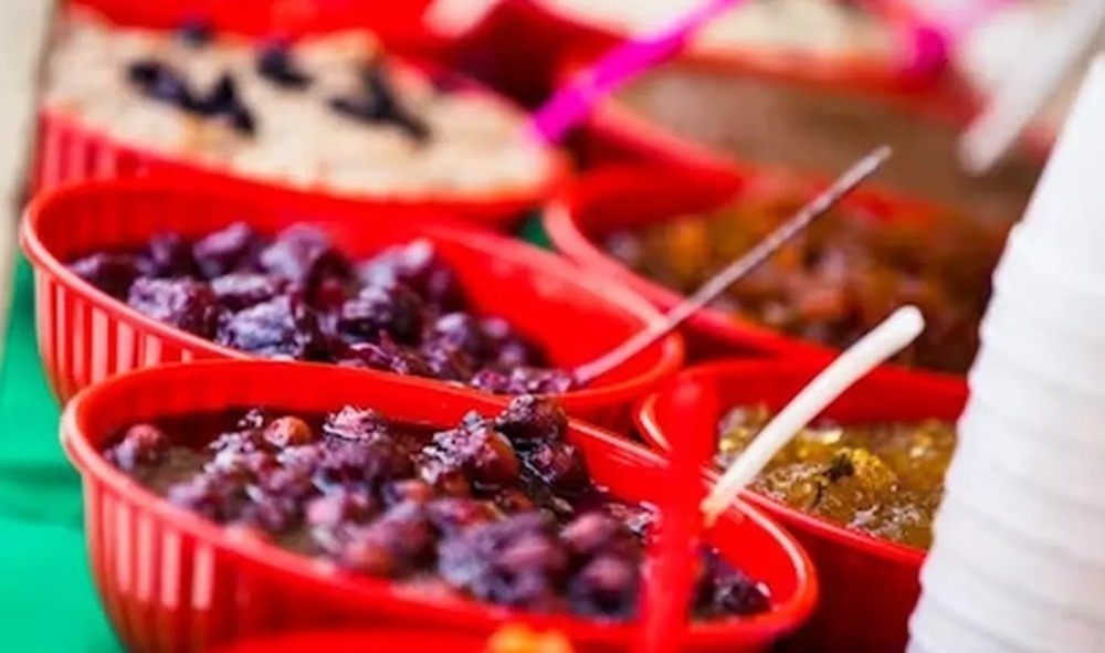 a row of red bowls filled with different types of food on a table .