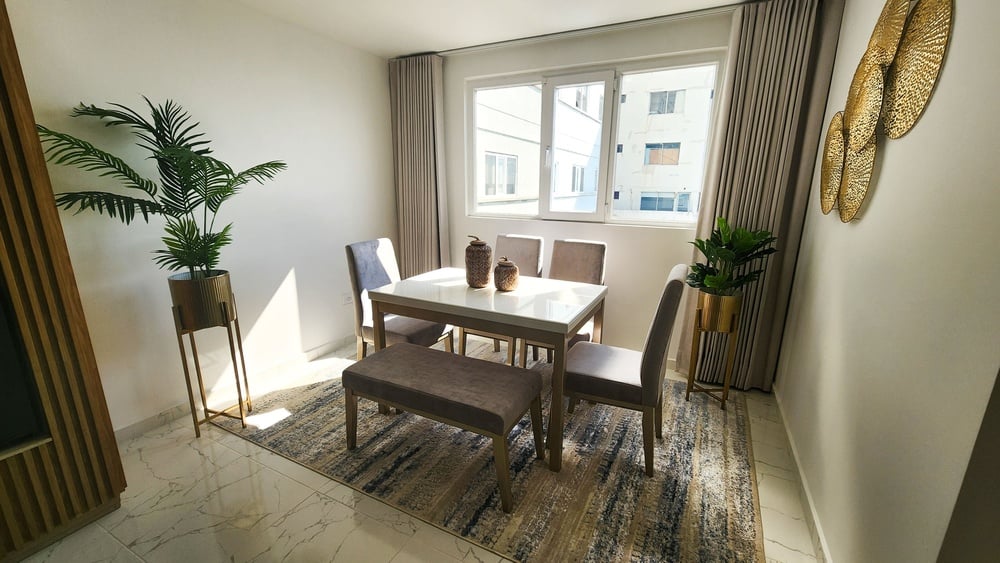 uma sala de jantar com mesa e cadeiras e uma grande janela