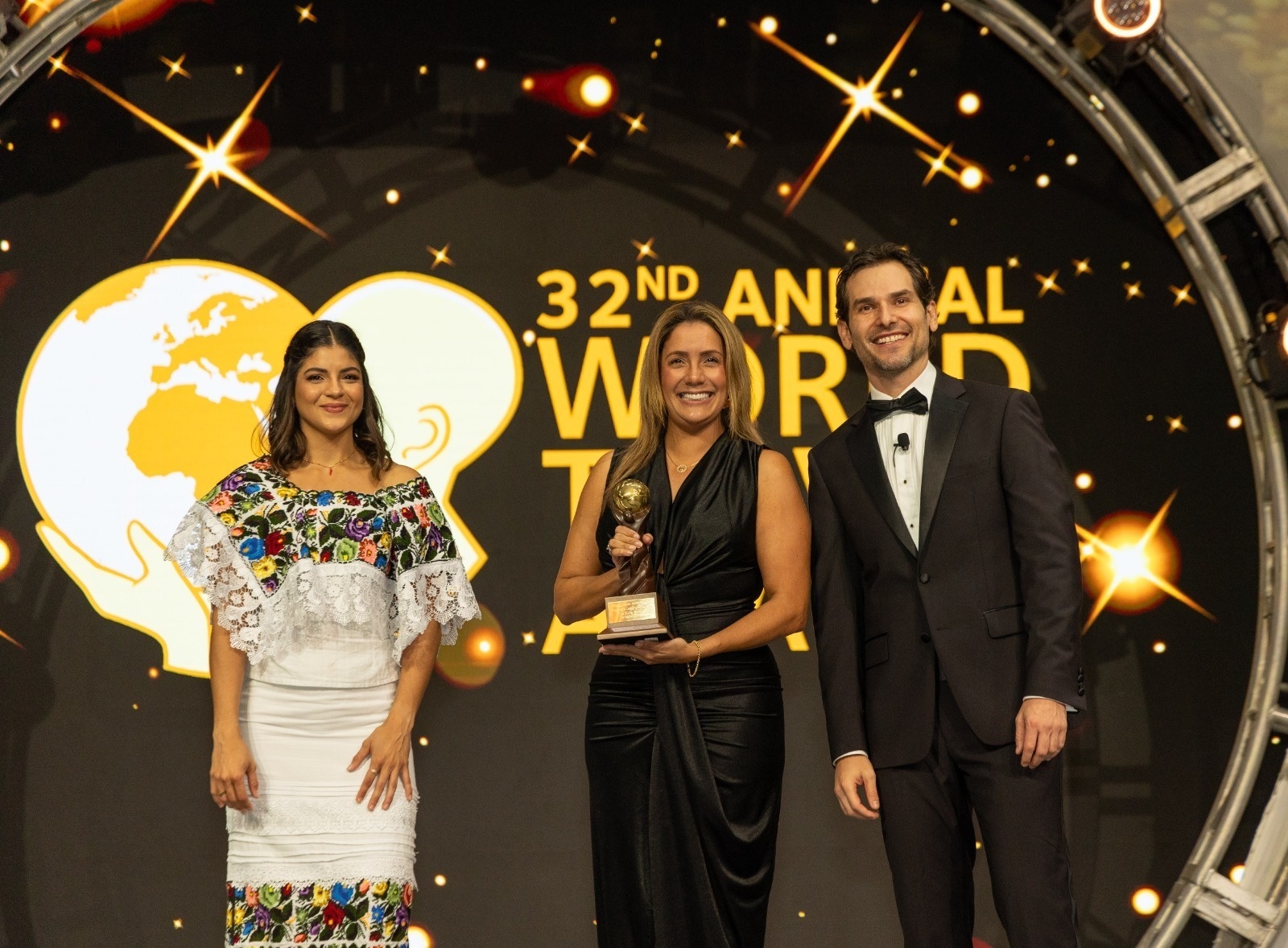 três pessoas estão em frente a uma tela que diz 32nd annual world