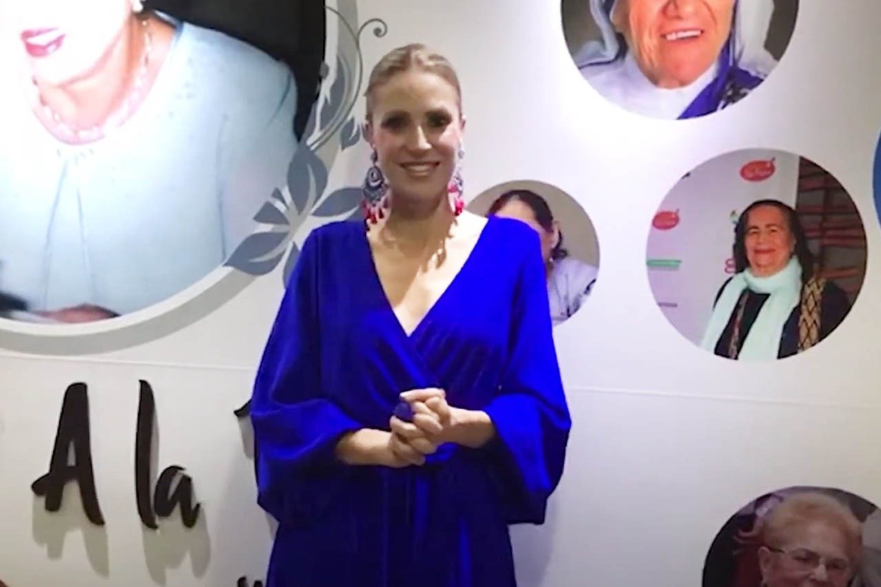 uma mulher em um vestido azul está em frente a uma parede com fotos de mulheres
