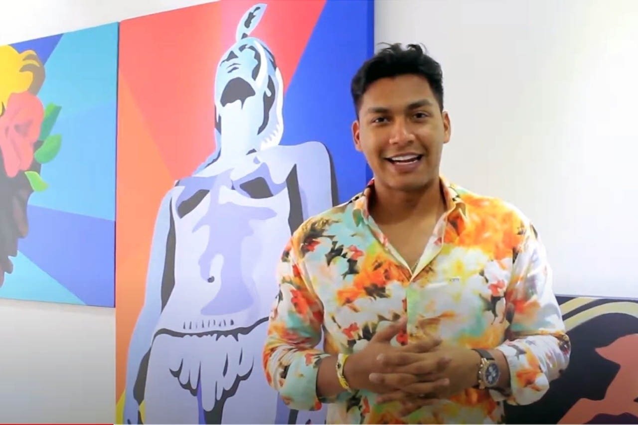 um homem de camisa colorida está em frente a uma pintura de uma mulher