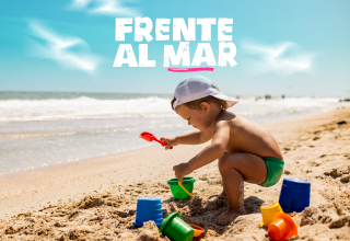 um menino brincando na areia na praia com frente al mar ao fundo