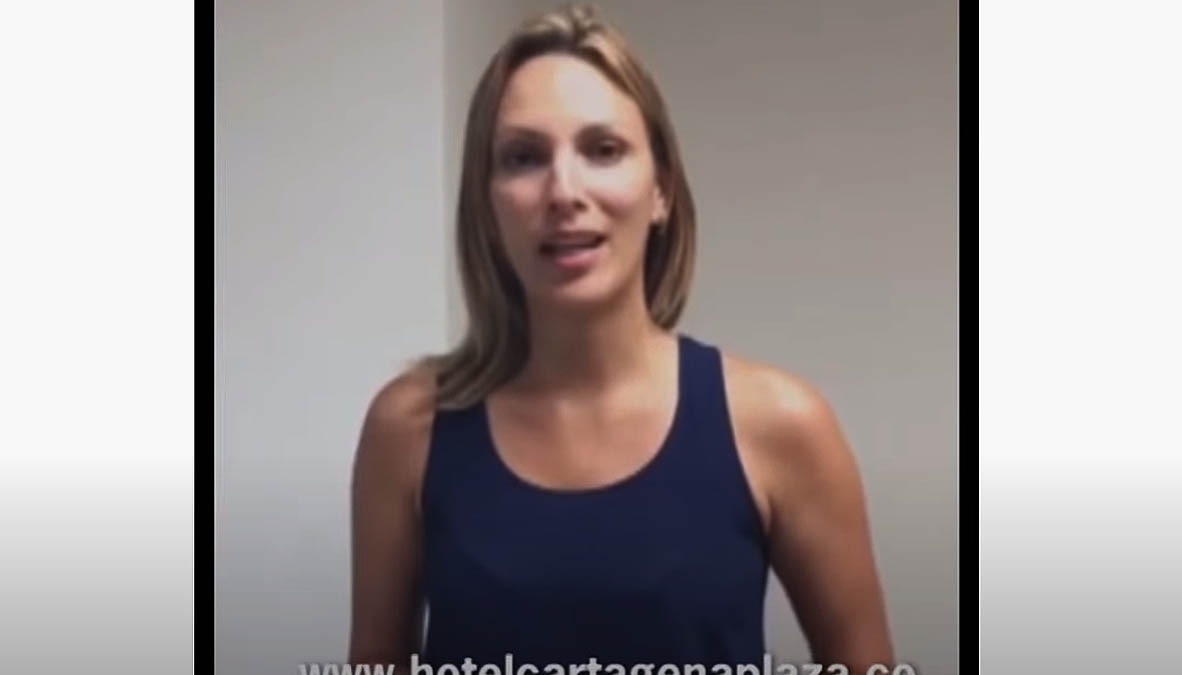 uma mulher está vestindo uma regata azul e sorrindo para a câmera .