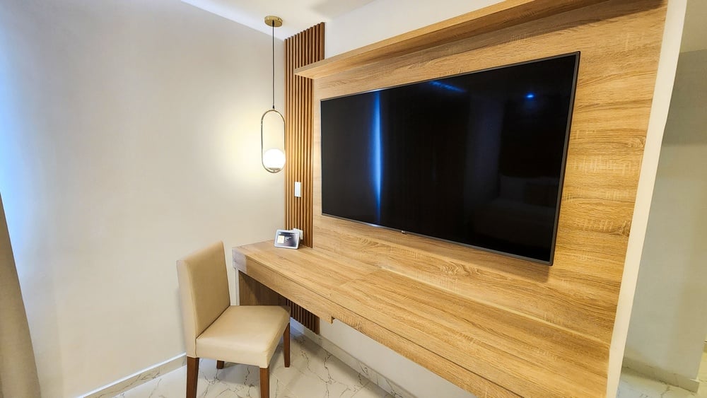 uma mesa de madeira e uma cadeira ao lado de um grande monitor de tv