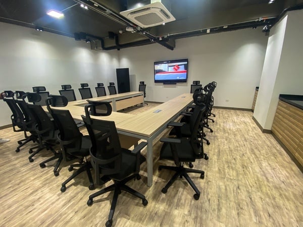 una sala de conferencias llena de sillas y una pantalla de televisión