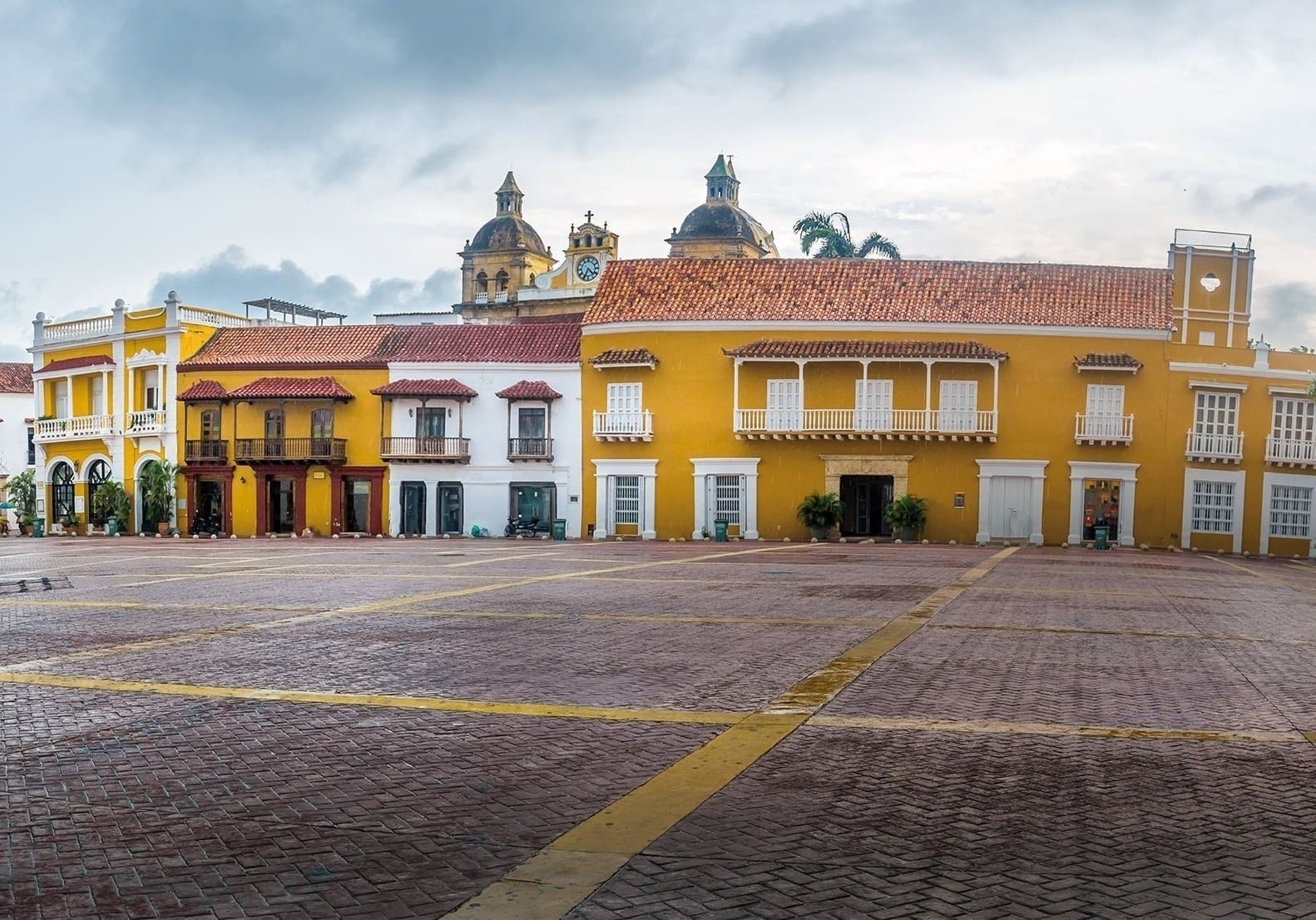 un edificio amarillo con balcones y una iglesia en el fondo
