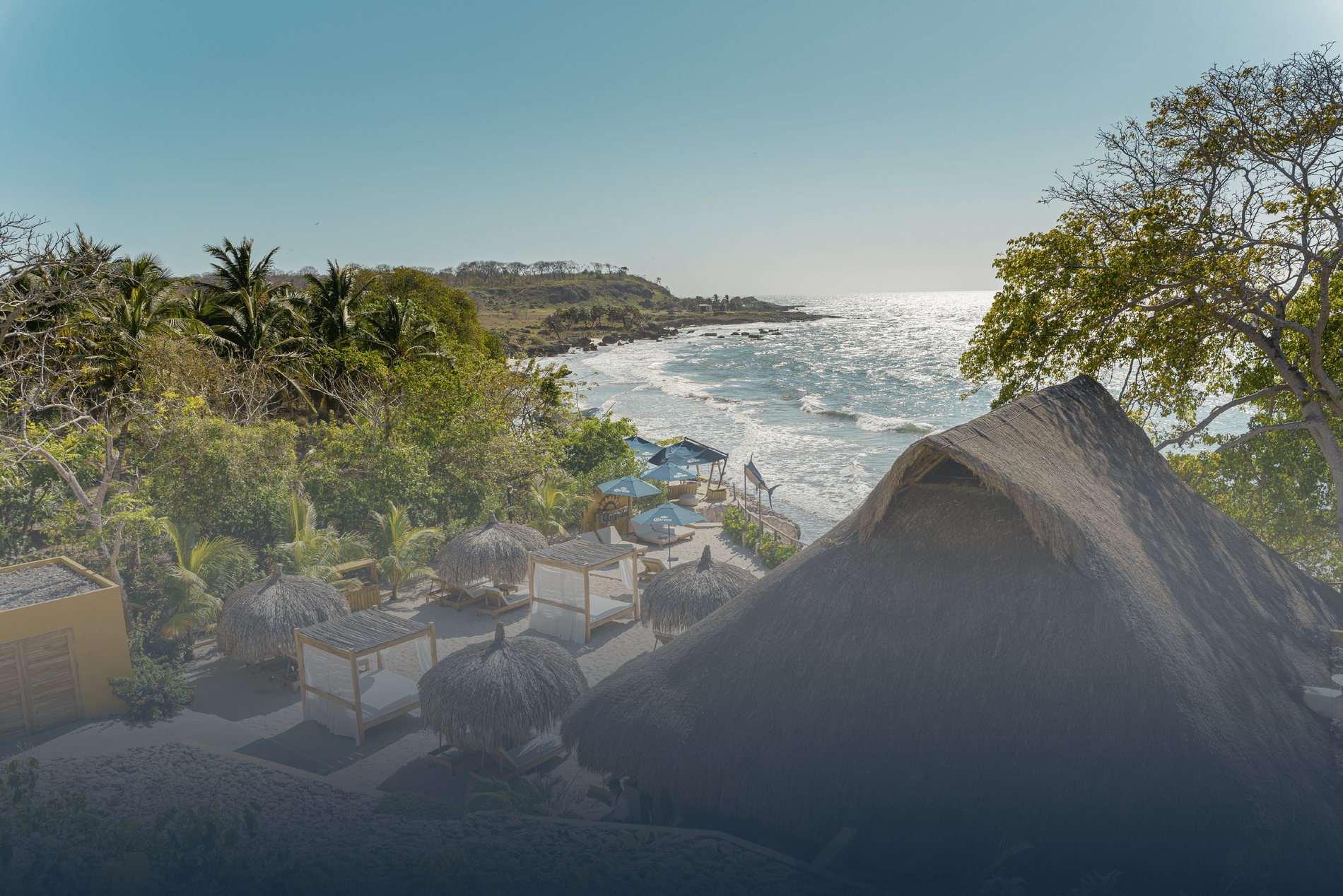 uma praia com cabanas e guarda-chuvas com vista para o oceano