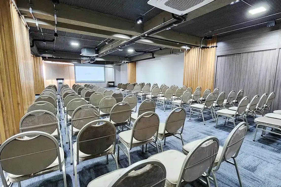 una sala de conferencias llena de sillas y una pantalla