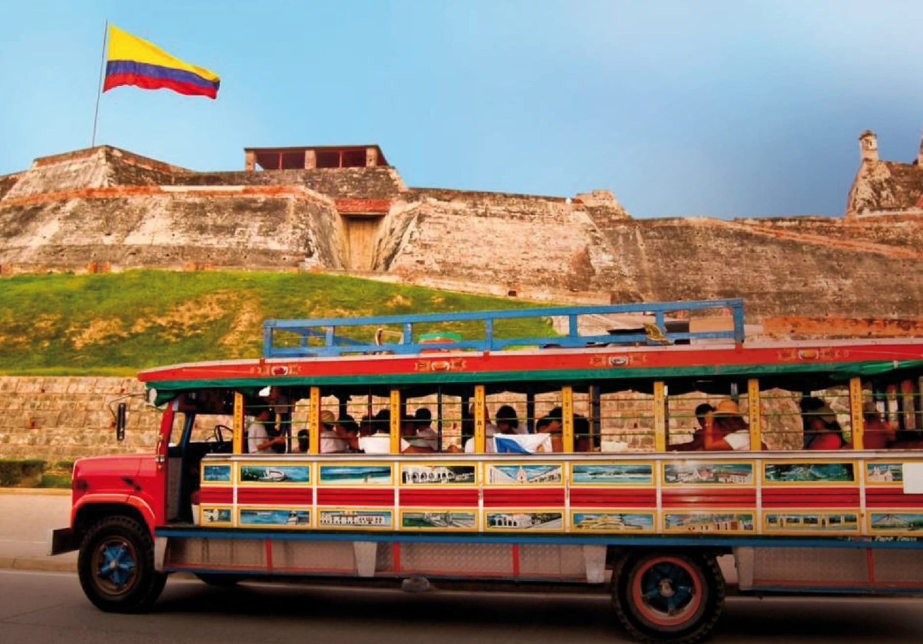 un autobús con la bandera de colombia en el fondo