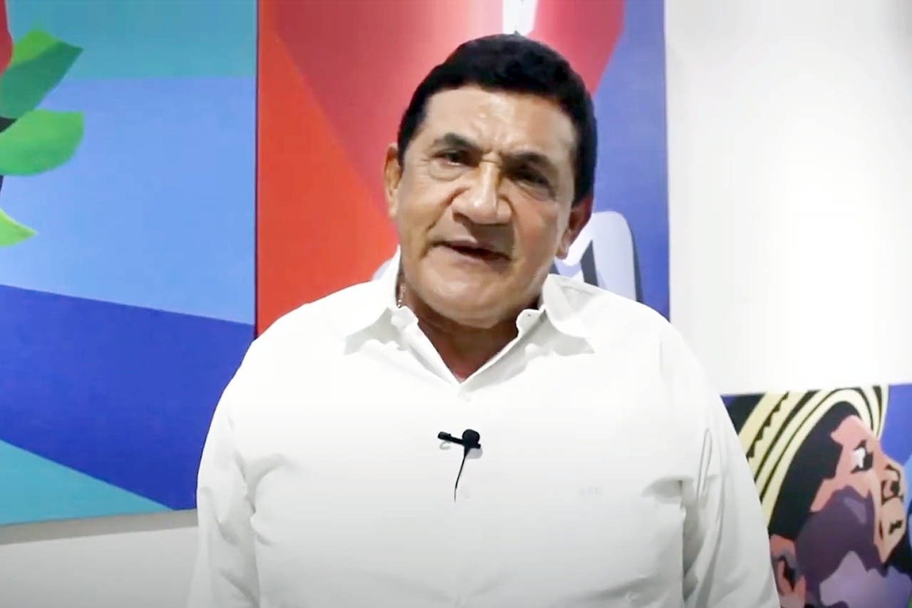 um homem vestindo uma camisa branca com um microfone na gola