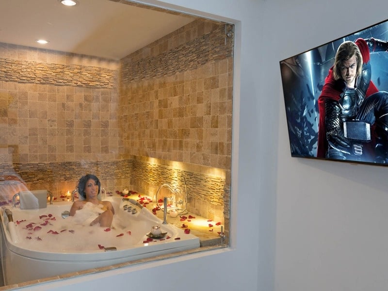 Chica disfrutando del Jacuzzi del hotel EM Cartagena Plaza mientras bebe una copa y ve una película