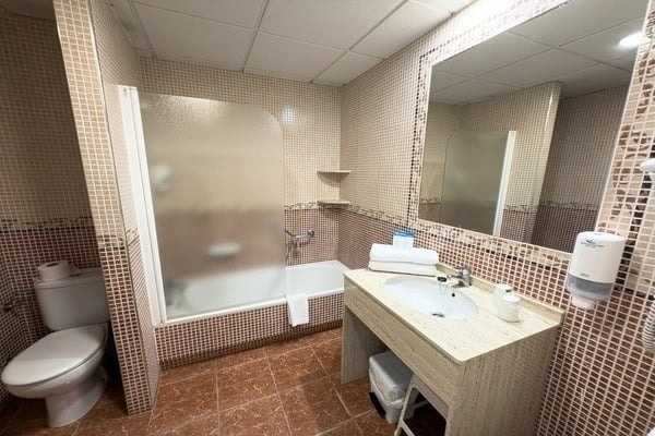 un baño con inodoro , lavabo , bañera y espejo .