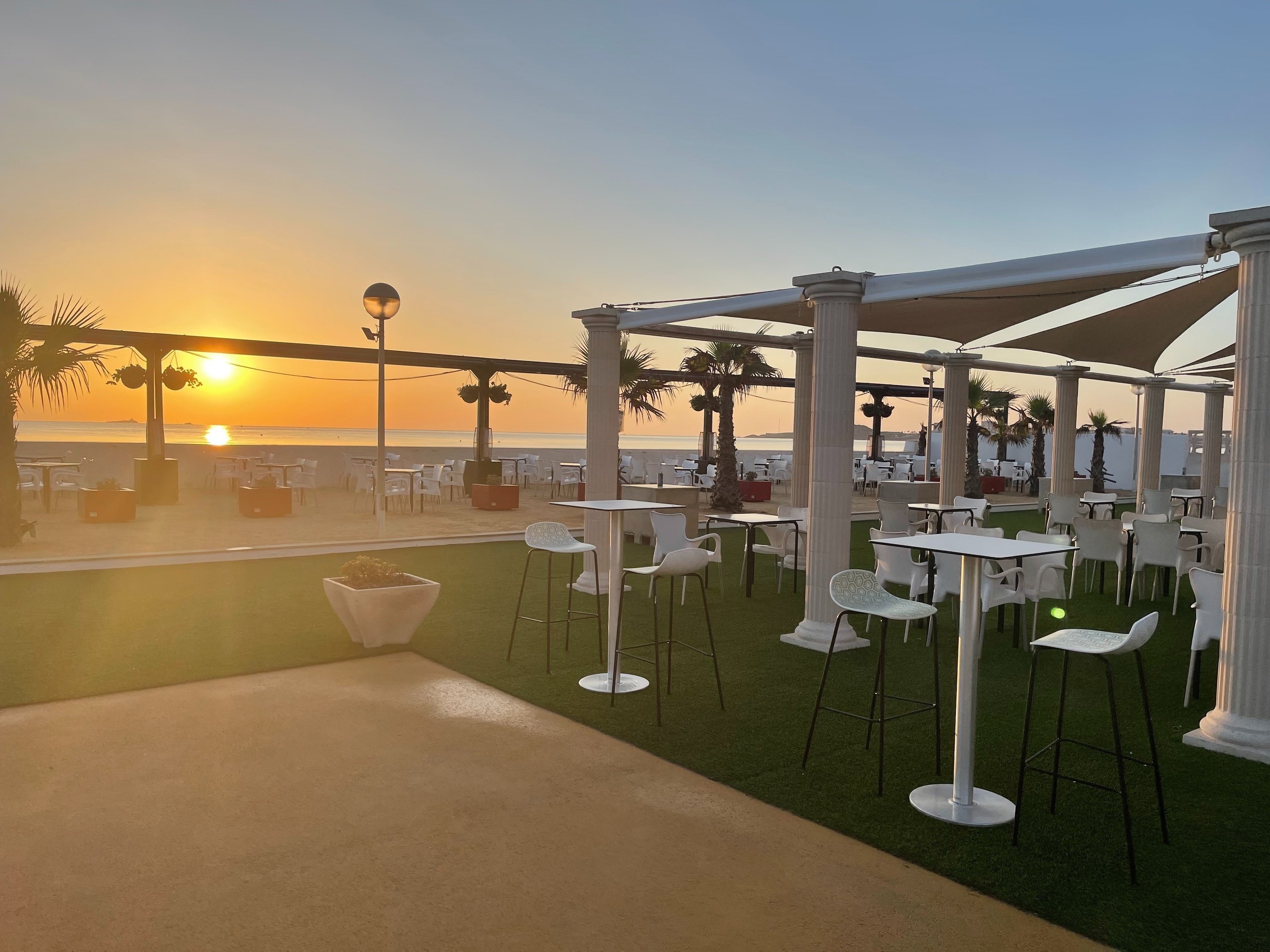 un patio con mesas y sillas al atardecer