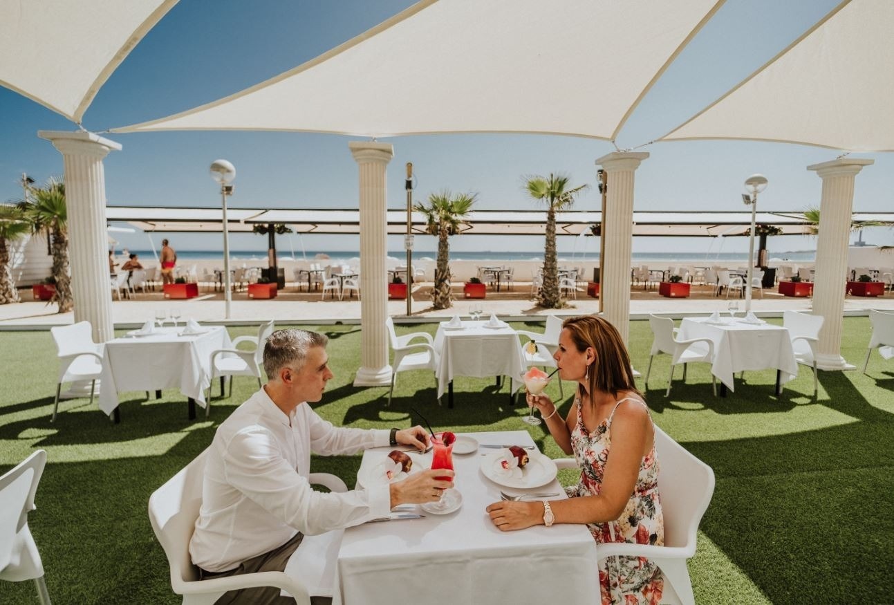 un hombre y una mujer están sentados en una mesa en un restaurante al aire libre
