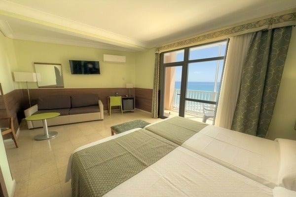 una habitación de hotel con dos camas , un sofá , una mesa y una televisión .