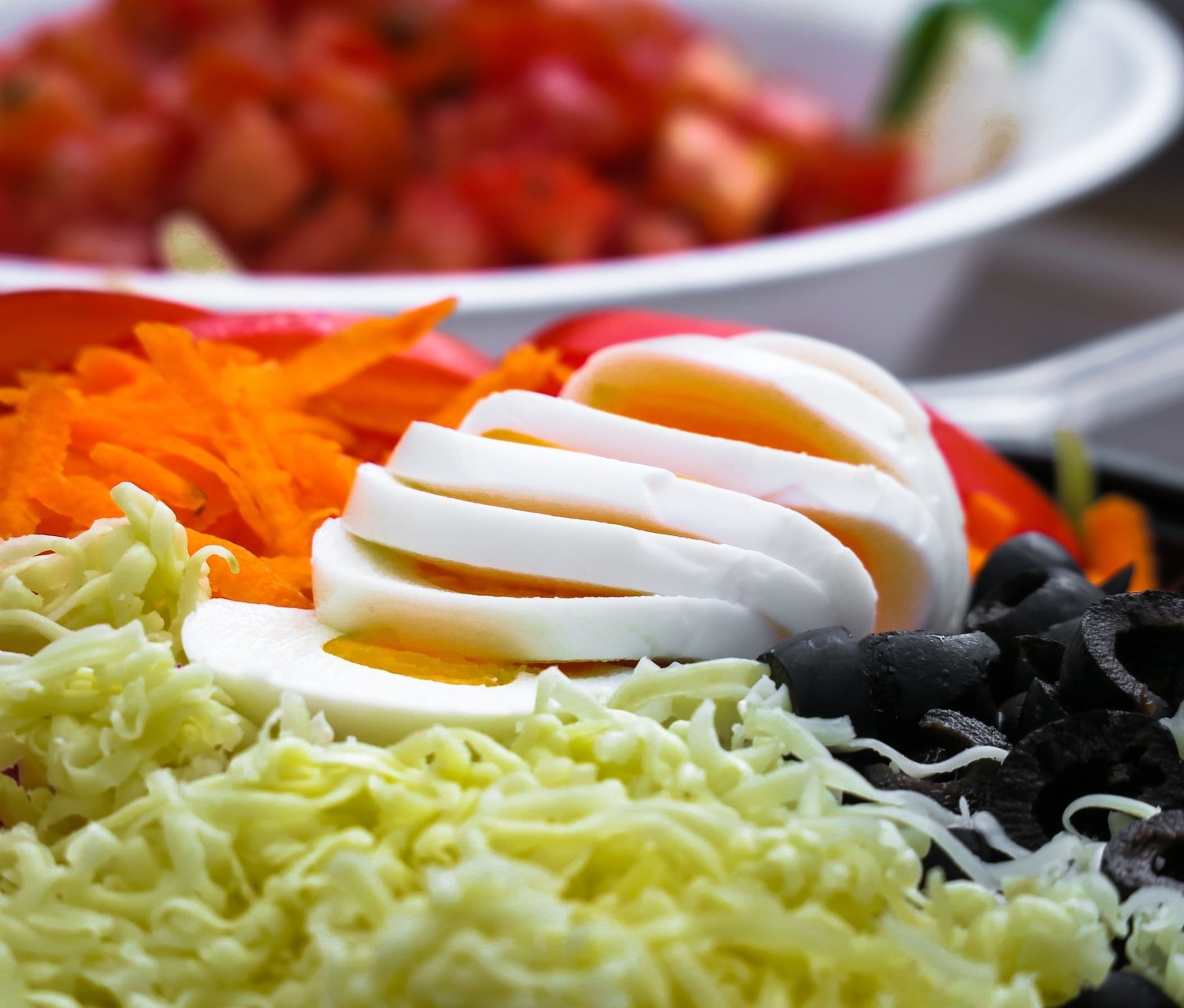a salad with hard boiled eggs carrots cheese and olives
