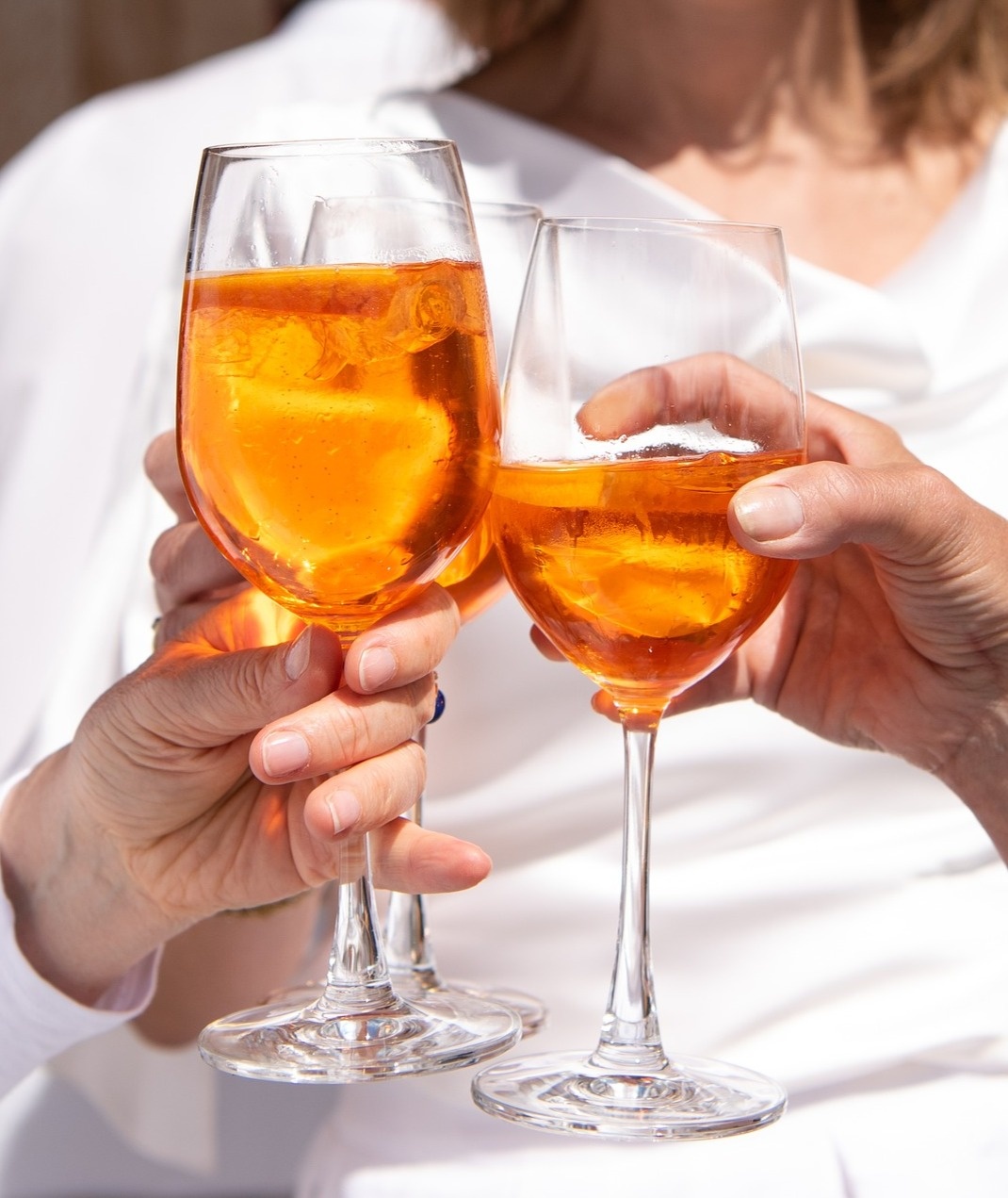 two people toasting with glasses of orange liquid