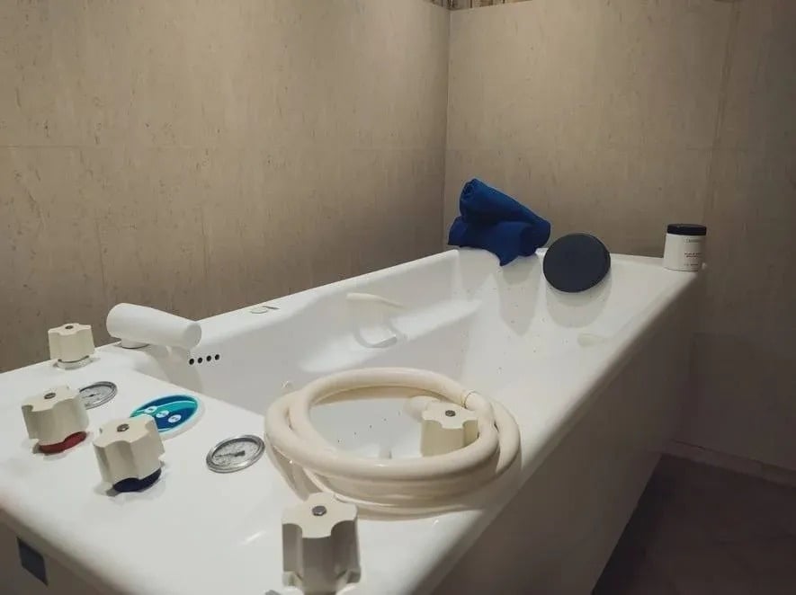 a bathtub with a hose attached to it and a bottle of salt