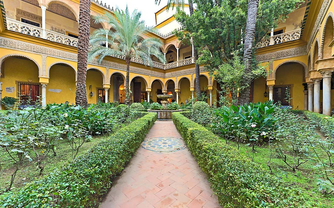 Patios interiores Epoca Suites: Casa del Gitano con fuente y vegetación exuberante en Sevilla