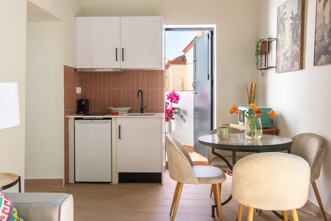 Un apartamento luminoso y acogedor con una cocina compacta, un comedor y una puerta que da a un patio exterior.
