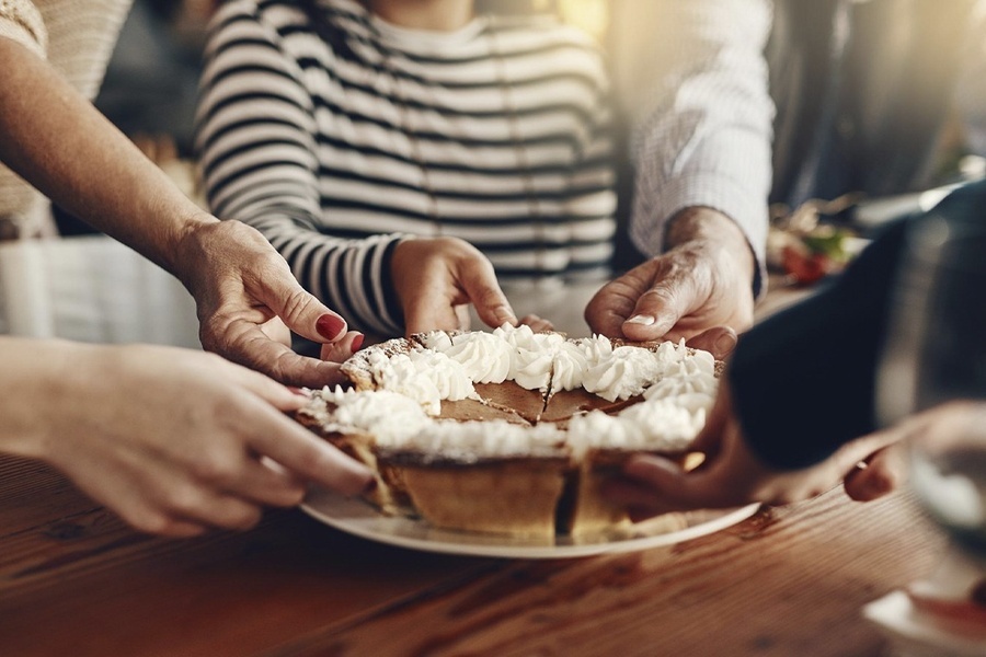 un grupo de personas sostiene un pastel de calabaza con crema batida