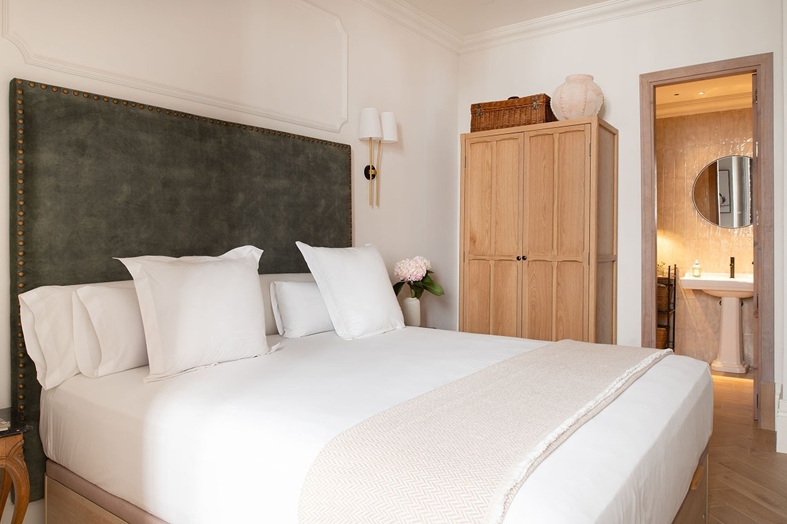 a bedroom with a green headboard and white sheets