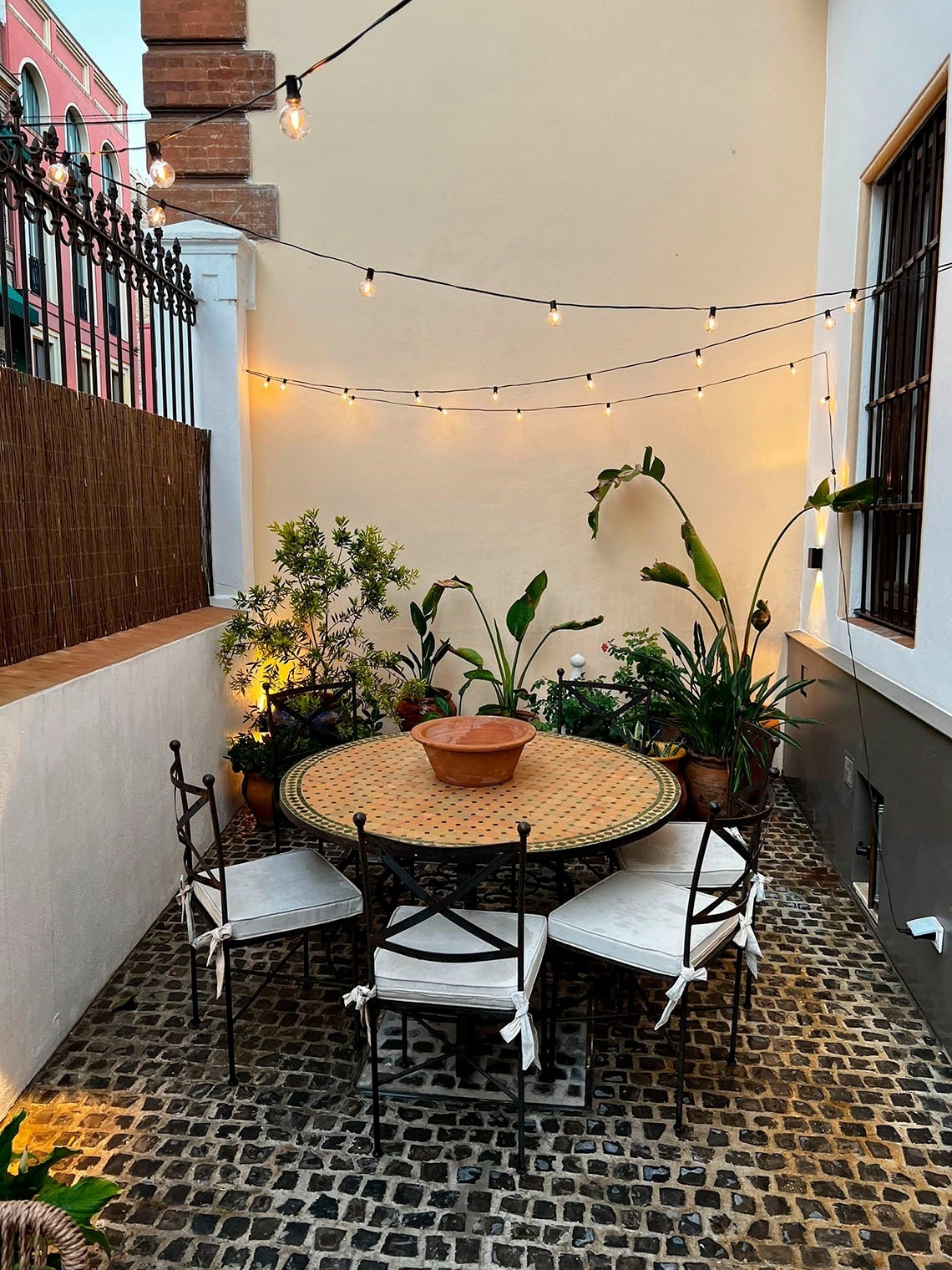 a patio with a table and chairs and a string of lights