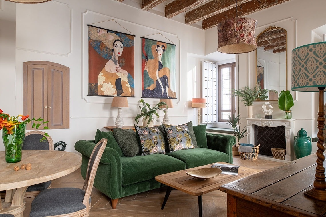 a living room with a green couch and two paintings on the wall