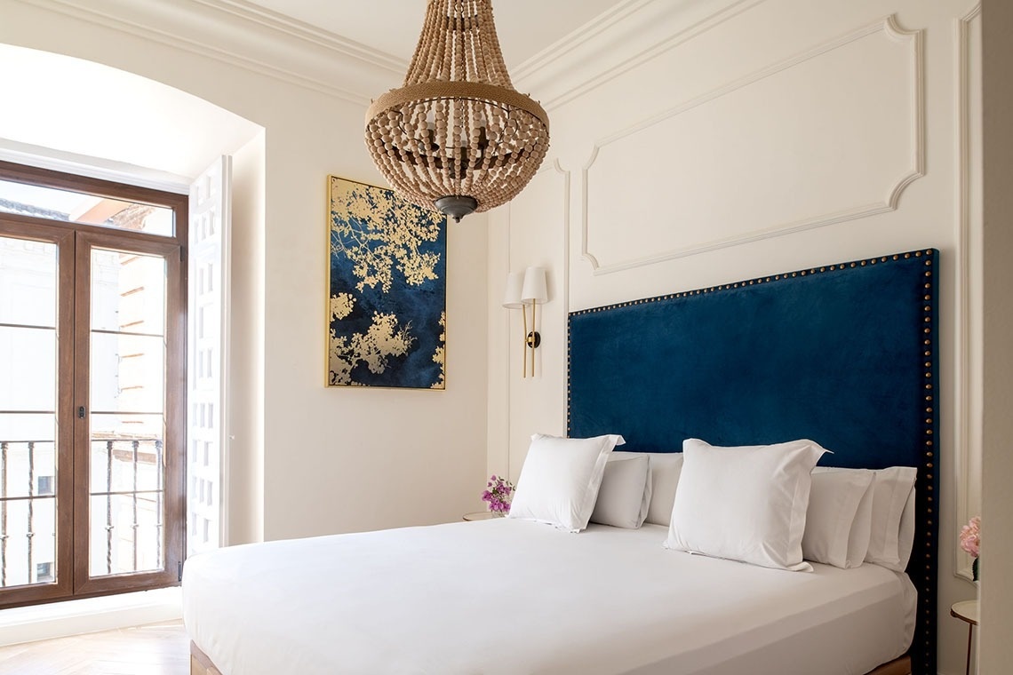 a bedroom with a blue headboard and a chandelier