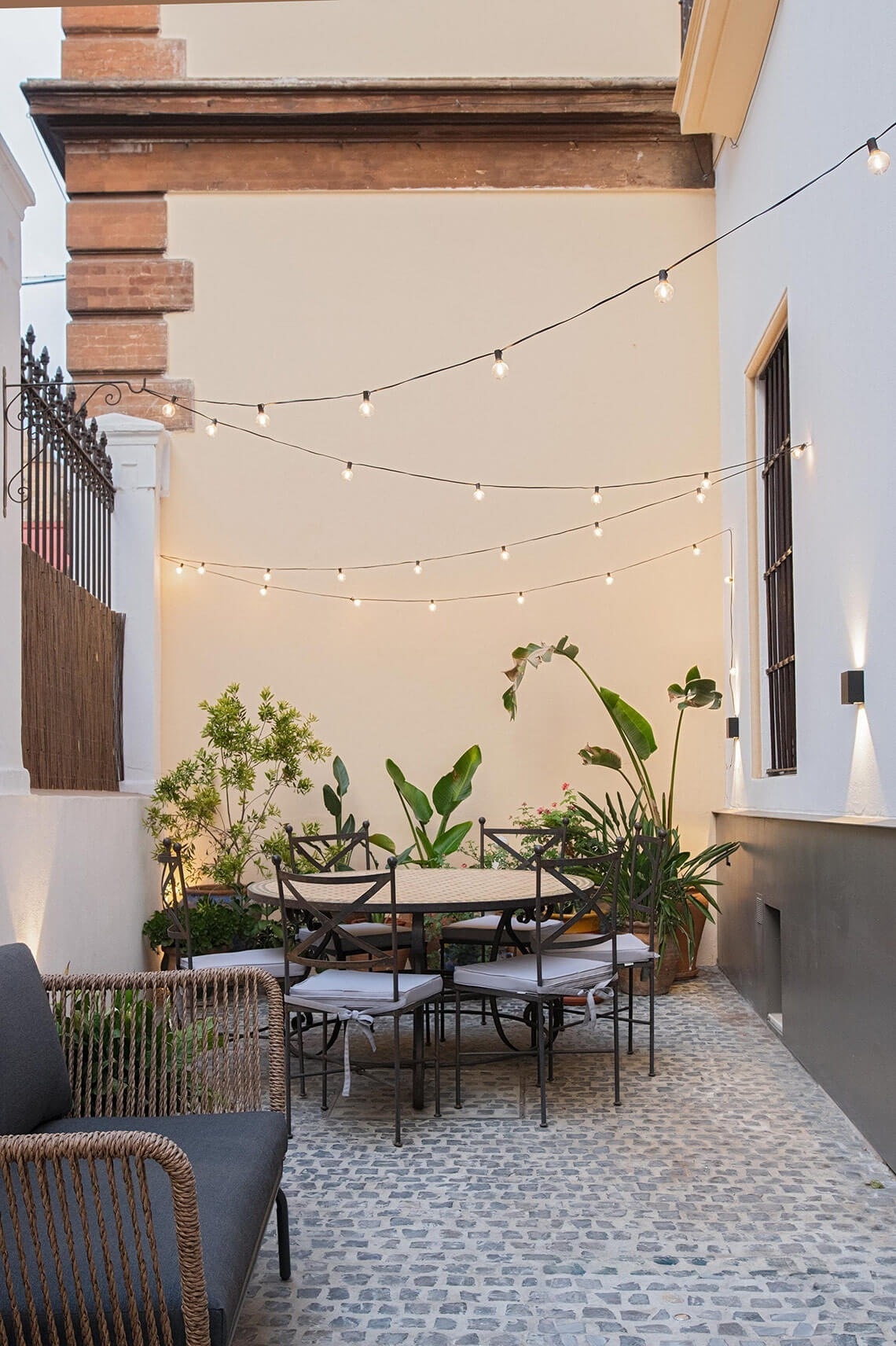 a patio with a table and chairs and a string of lights