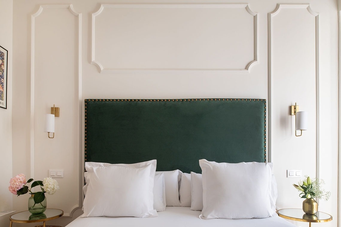 a bed with a green headboard and white pillows