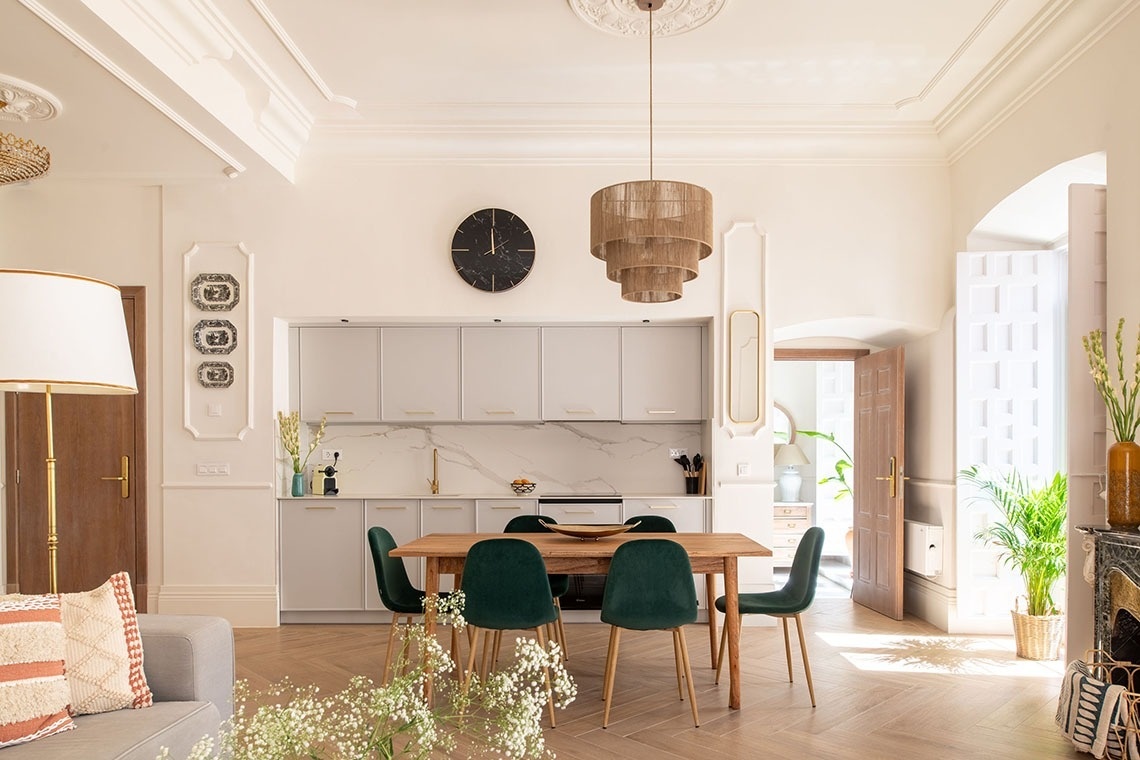 una mesa de comedor con sillas verdes y un reloj en la pared