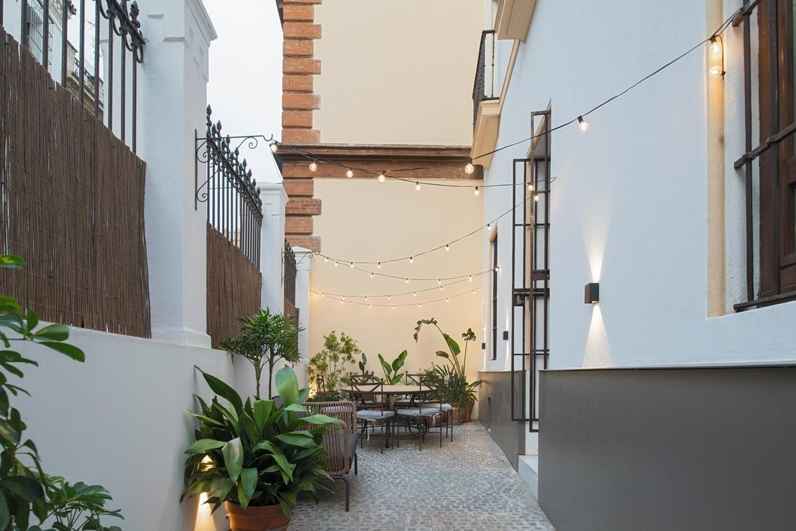 a narrow alleyway with a table and chairs and a string of lights