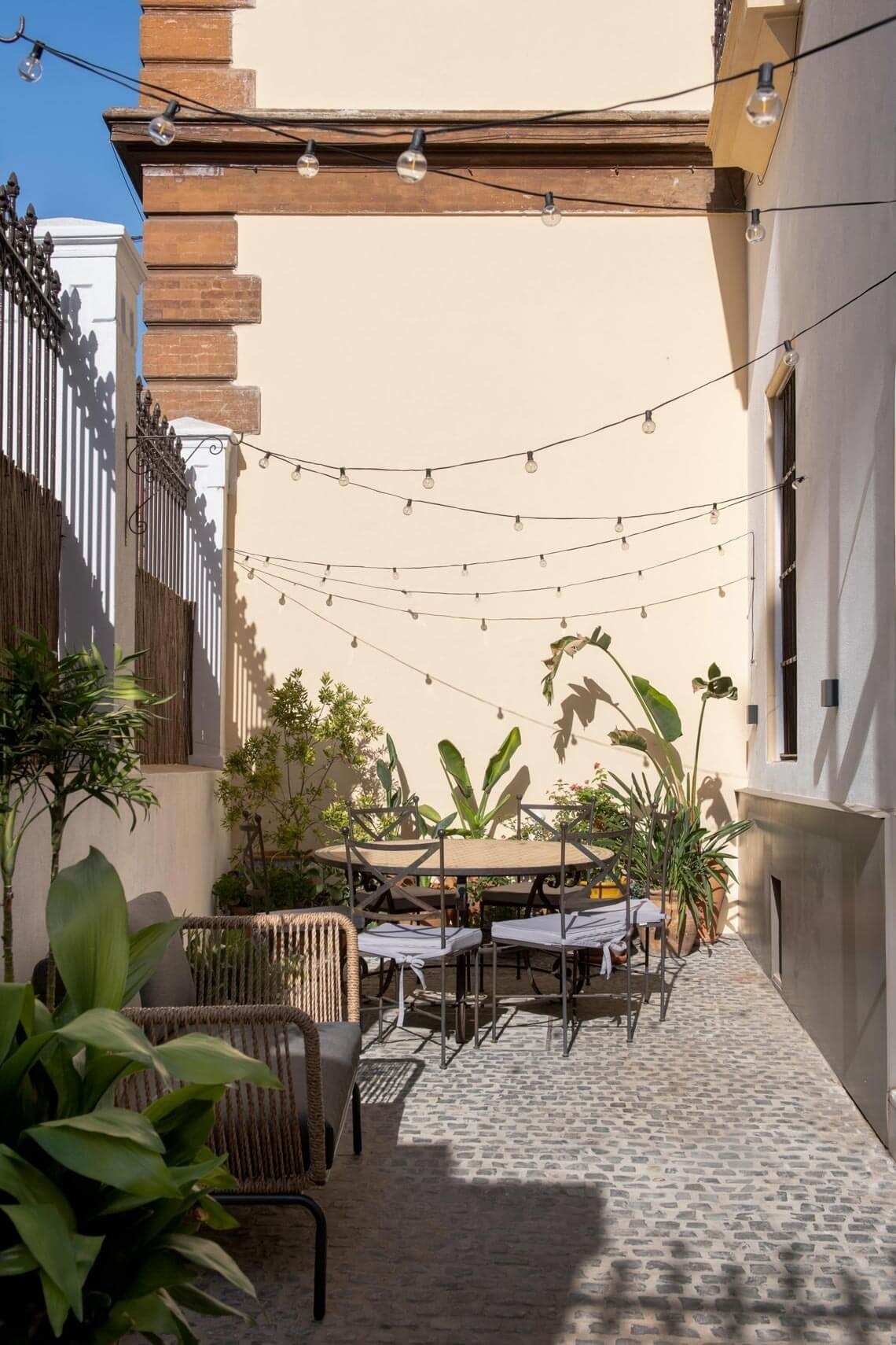 a patio with a table and chairs and a string of lights